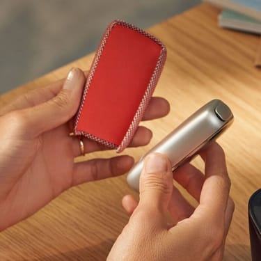 Ruce držící červený textilní zadní panel red a zařízení Ploom X Advanced