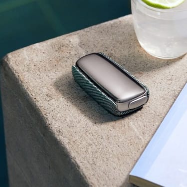 Fotka zařízení Ploom X Advanced v zeleném, látkovém krytu u bazénu
